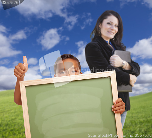 Image of Young Boy with Blank Chalk Board, Teacher Behind on Grass