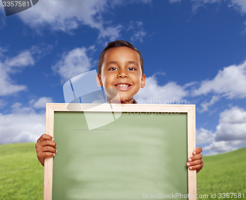 Image of Happy Hispanic Boy In Grass Field Holding Blank Chalk Board