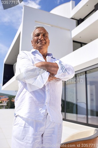 Image of senior man in front of modern home