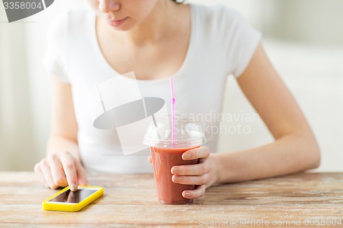 Image of close up of woman with smartphone and smoothie