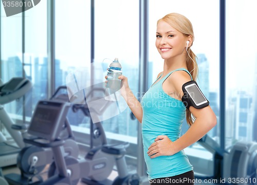 Image of smiling sporty woman with smartphone and earphones