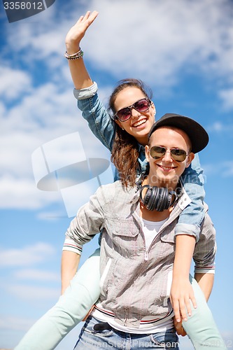 Image of smiling teenagers in sunglasses having fun outside