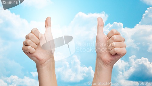 Image of woman hands showing thumbs up over blue sky