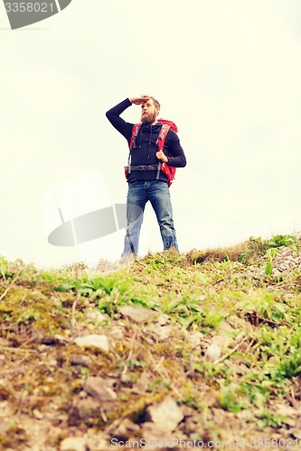 Image of tourist with beard and backpack looking far away