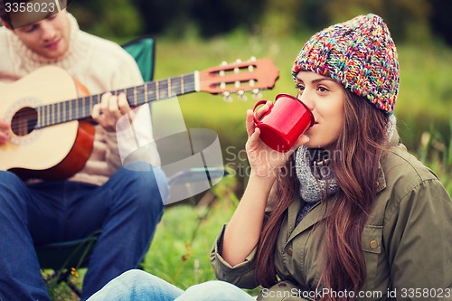 Image of smiling couple with guitar in camping