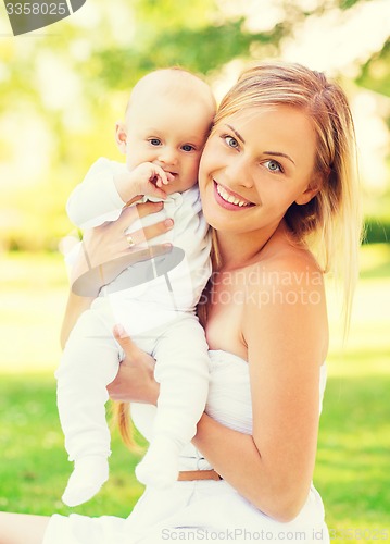 Image of happy mother with little baby sitting on blanket