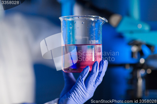 Image of close up of hand holding glass in chemical lab