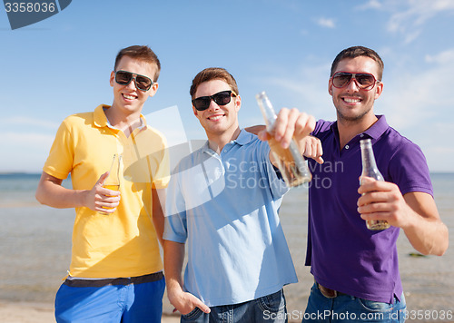 Image of happy friends with beer bottles on beach