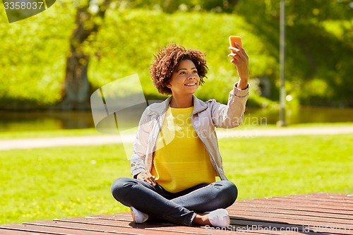 Image of happy african woman taking selfie with smartphone