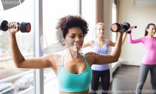 Image of group of happy women with dumbbells in gym