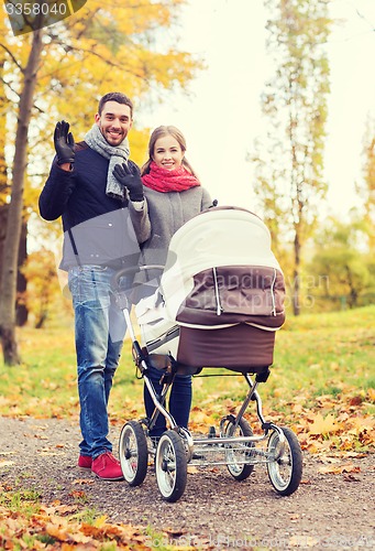 Image of smiling couple with baby pram in autumn park