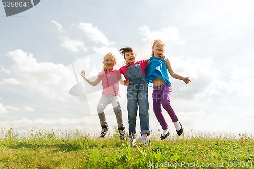 Image of group of happy kids jumping high on green field