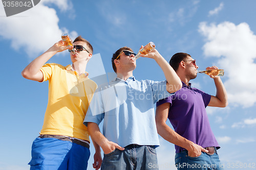 Image of happy friends with beer bottles on beach