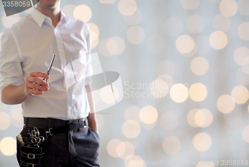 Image of close up of male stylist with scissors over lights