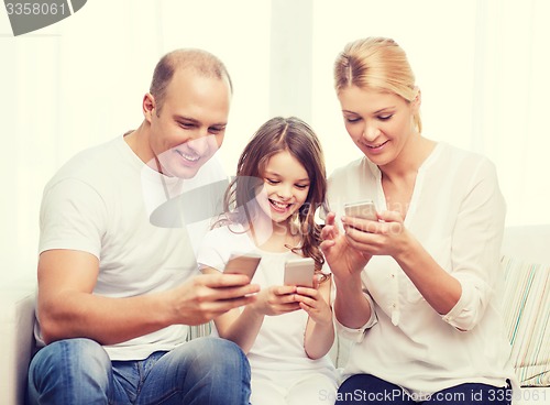 Image of parents and little girl with smartphones at home