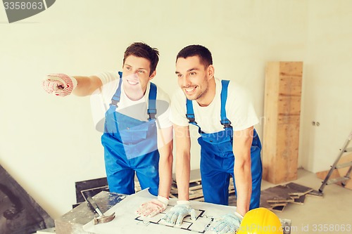 Image of smiling builders with blueprint