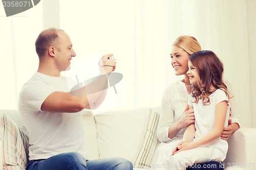 Image of happy father taking picture of mother and daughter