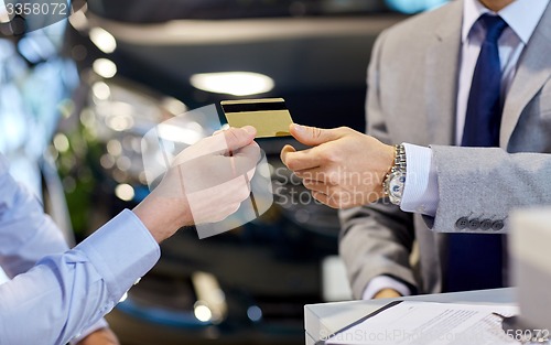 Image of customer giving credit card to car dealer in salon