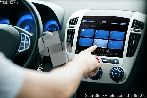 Image of hand pushing button on car control panel screen