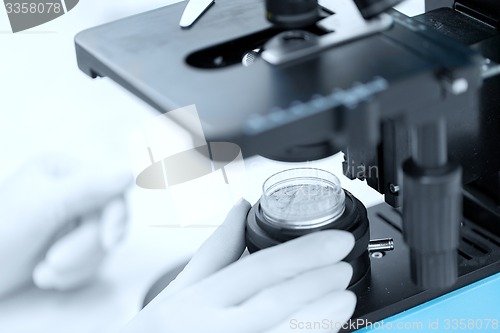 Image of close up of hand with microscope and powder sample