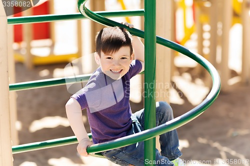 Image of happy little boy climbing on children playground