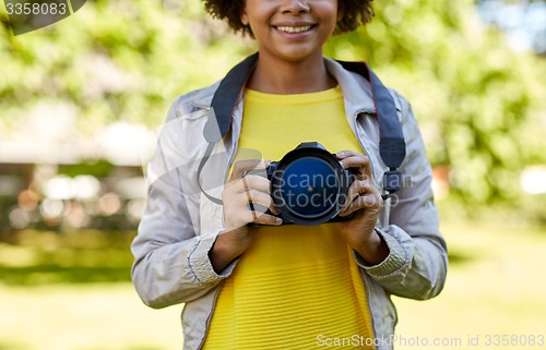 Image of happy african woman with digital camera in park