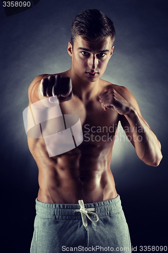 Image of young man on fighting stand over black background