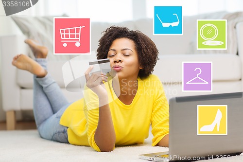 Image of happy african woman with laptop and credit card