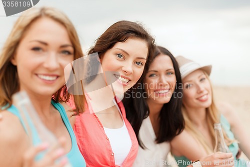 Image of smiling girls with drinks on the beach