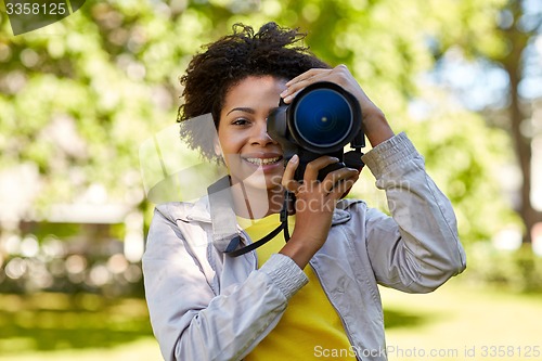 Image of happy african woman with digital camera in park