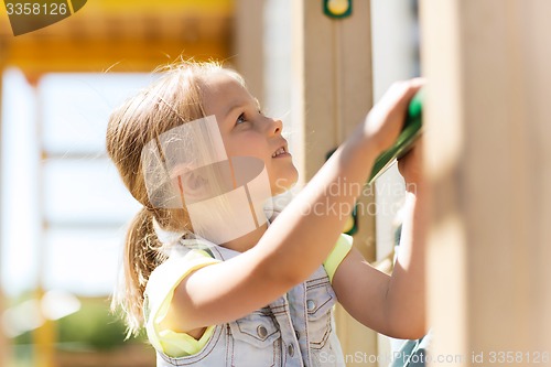 Image of happy little girl climbing on children playground