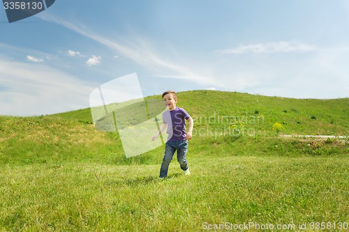 Image of happy little boy running on green field outdoors