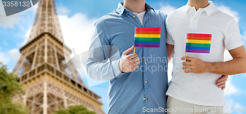 Image of close up of male gay couple with rainbow flags