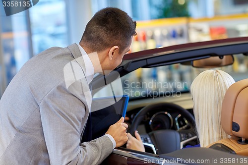 Image of woman and car dealer with tablet pc in auto salon