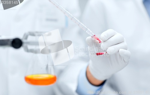 Image of close up of scientists filling test tube in lab