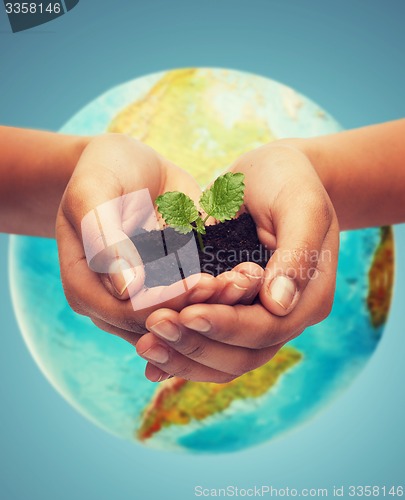 Image of woman hand with green sprout over earth globe