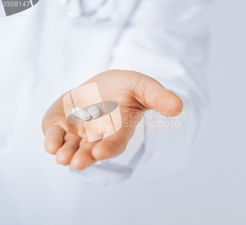 Image of doctor hands giving white pills 