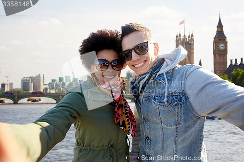 Image of happy teenage couple taking selfie in london city