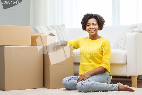 Image of happy african woman with cardboard boxes at home