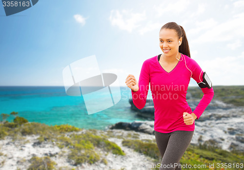 Image of smiling young african woman running on beach