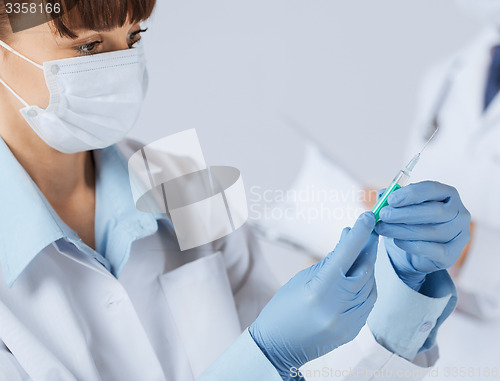 Image of female doctor holding syringe with injection