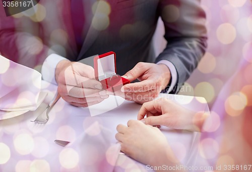 Image of excited young woman and boyfriend giving her ring