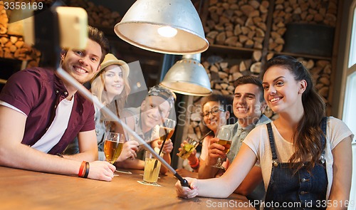 Image of friends with smartphone on selfie stick at bar