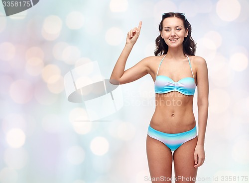 Image of happy woman in bikini swimsuit pointing finger up
