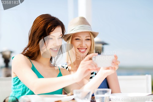 Image of girls taking photo in cafe on the beach