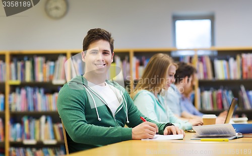 Image of happy student boy reading books in library