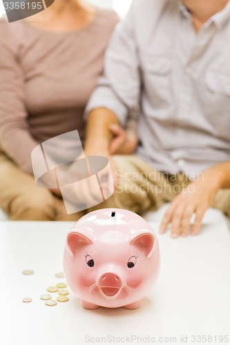 Image of close up of couple with coins and piggy bank