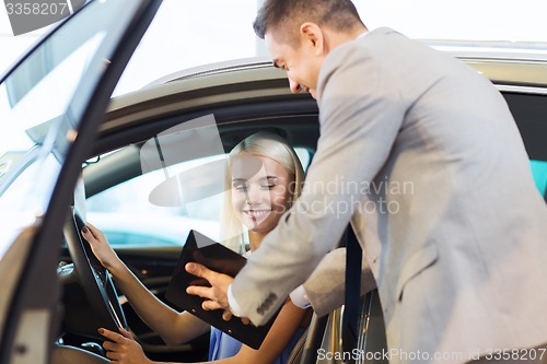 Image of happy woman with car dealer in auto show or salon