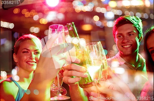 Image of smiling friends with wine glasses and beer in club