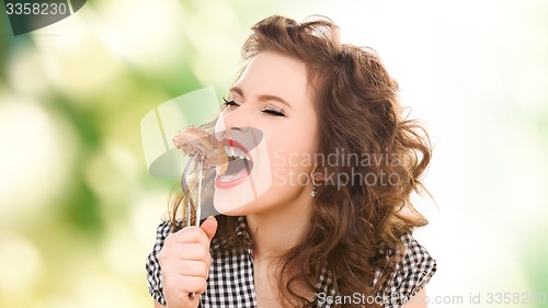 Image of hungry young woman eating meat on fork over green